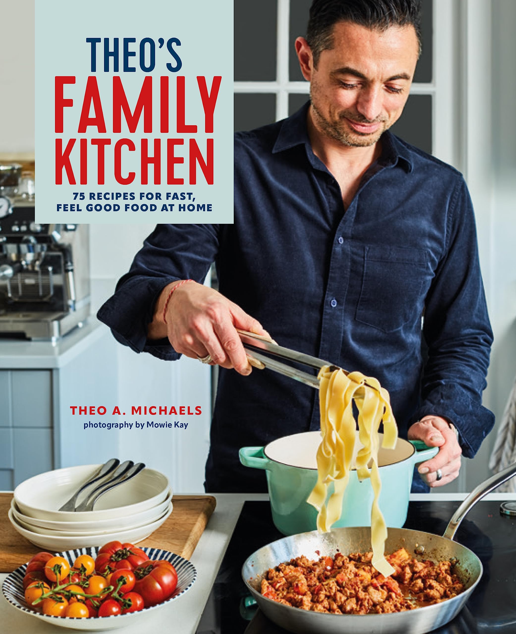 Hardback book "Theo's Family Kitchen" by Theo A. Michaels featuring 75 recipes on a wooden kitchen table background.