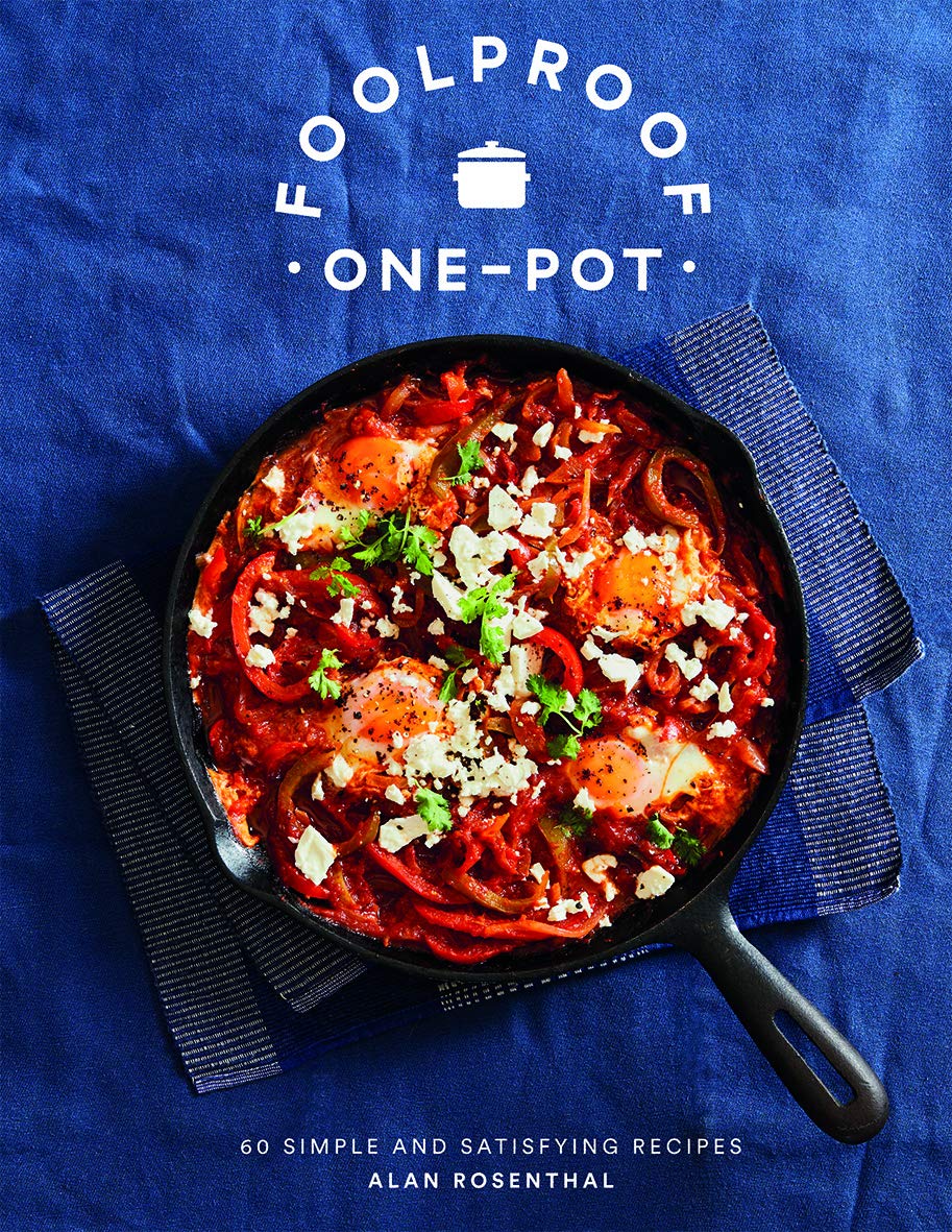 Hardback copy of "Foolproof One-Pot" by Alan Rosenthal with 60 simple recipes displayed on a wooden kitchen table.