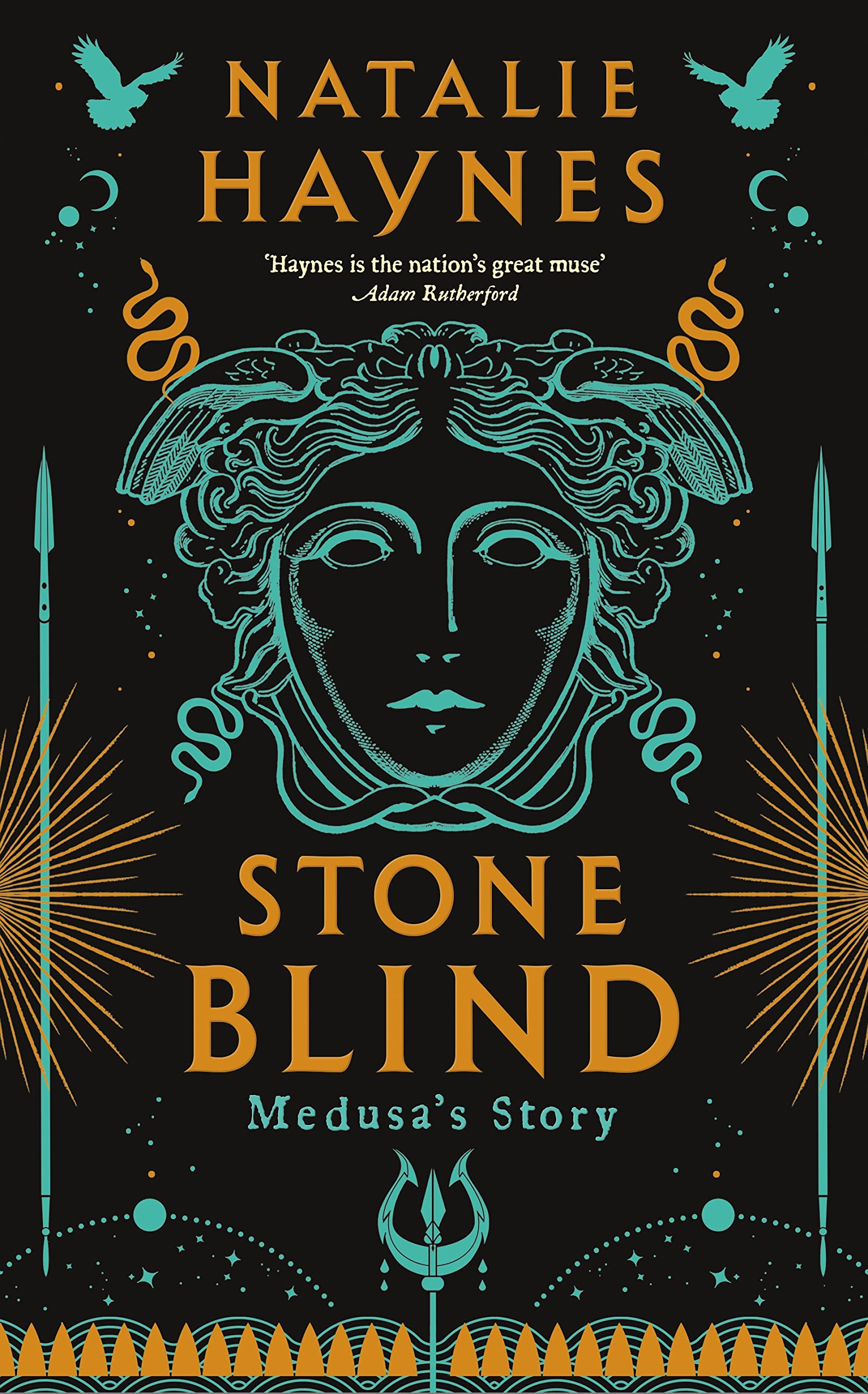 Hardback fiction book "Stone Blind" by Natalie Haynes displayed on a mantle with a cozy reading nook in the background.