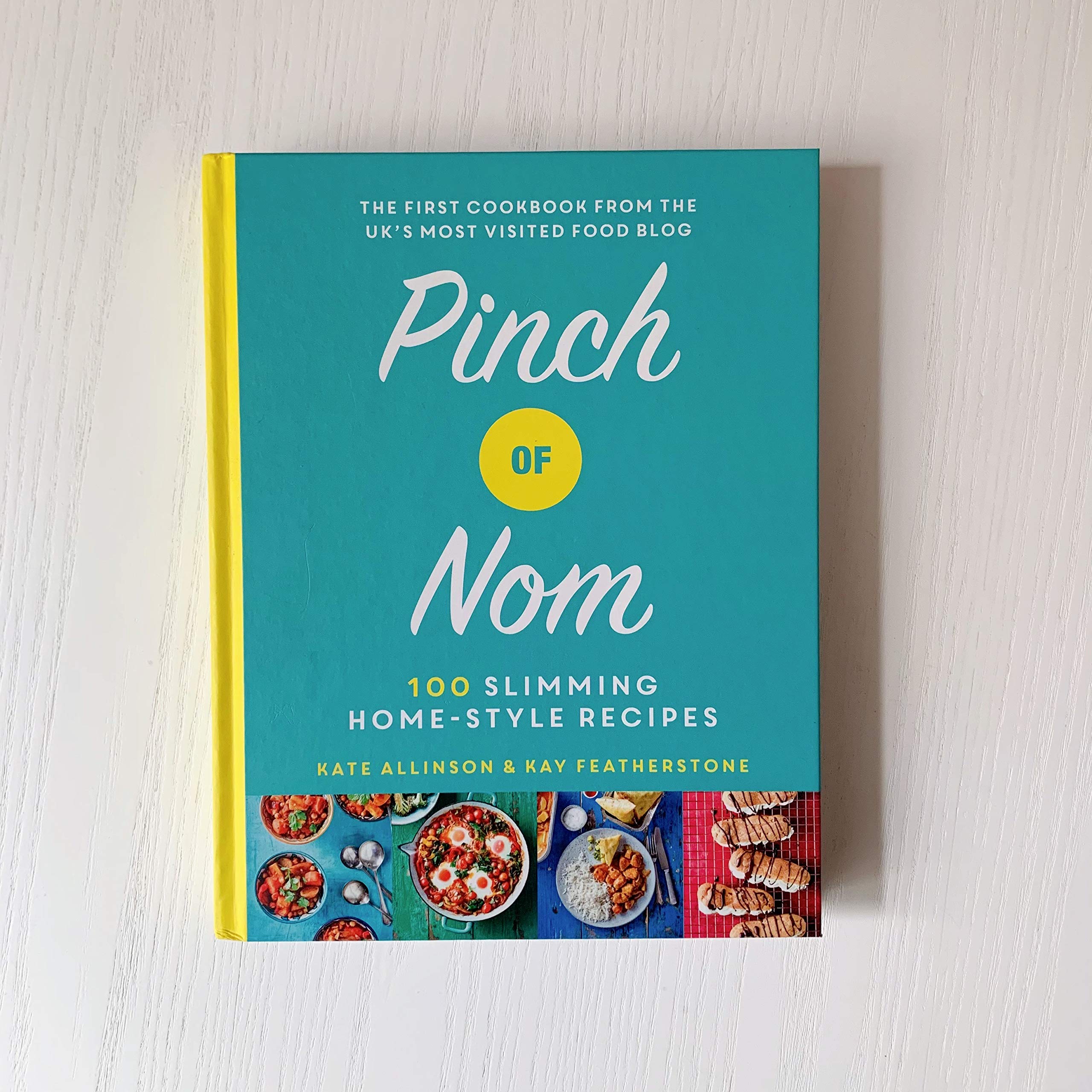 Hardback copy of "Pinch of Nom" by Kay Featherstone and Kate Allinson, showcasing the book cover design and title.