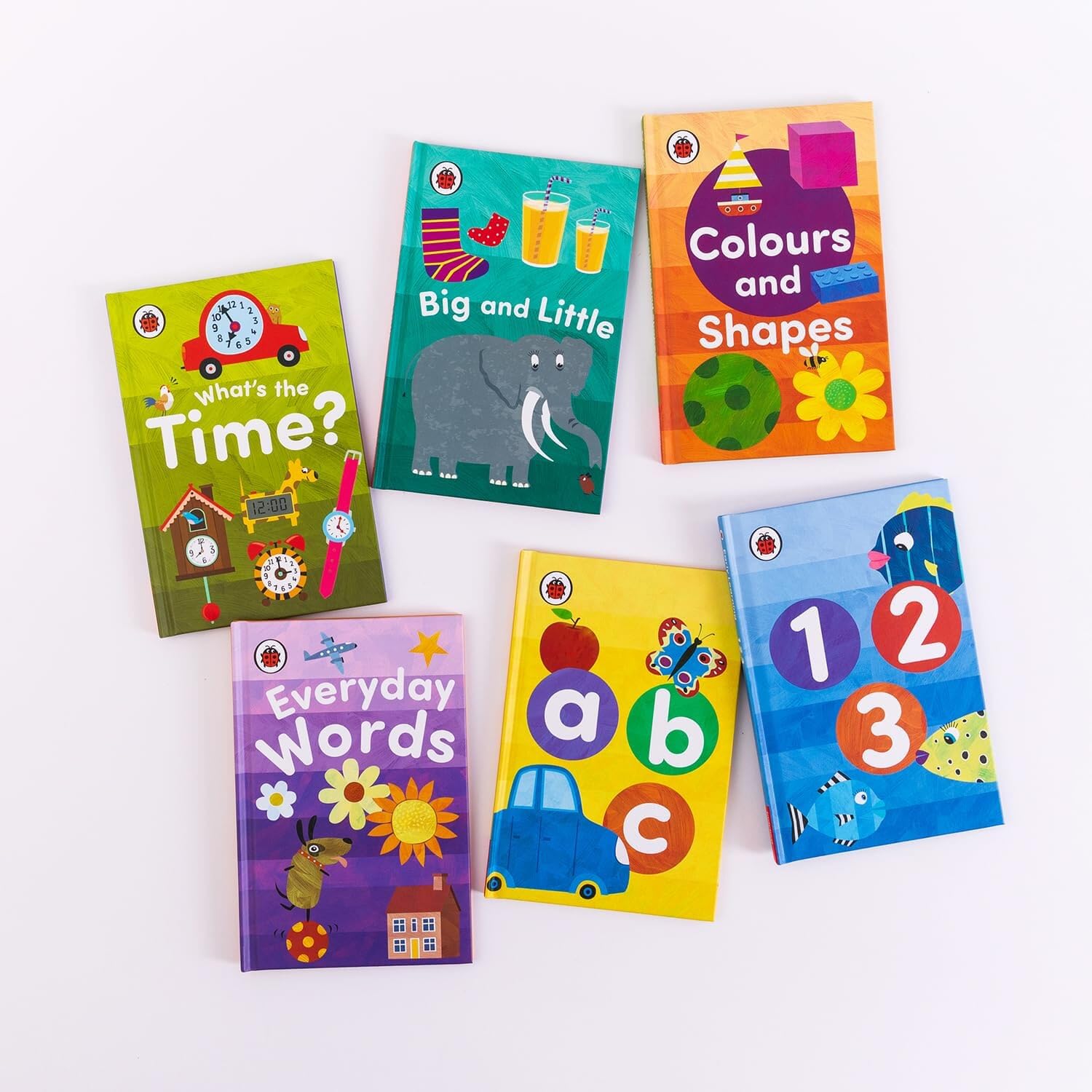 All six Ladybird Early Learning Library paperback books fanned out beside the tuck-box, showing titles ABC, 123, Colours and Shapes, Everyday Words, Big and Little, and What's the Time?